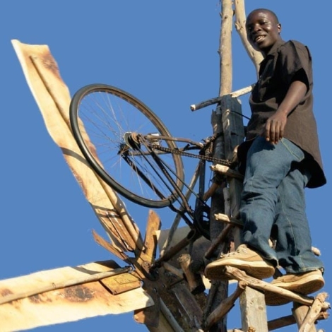 Kamkwamba up in his wind turbine power generator made from bicycle parts