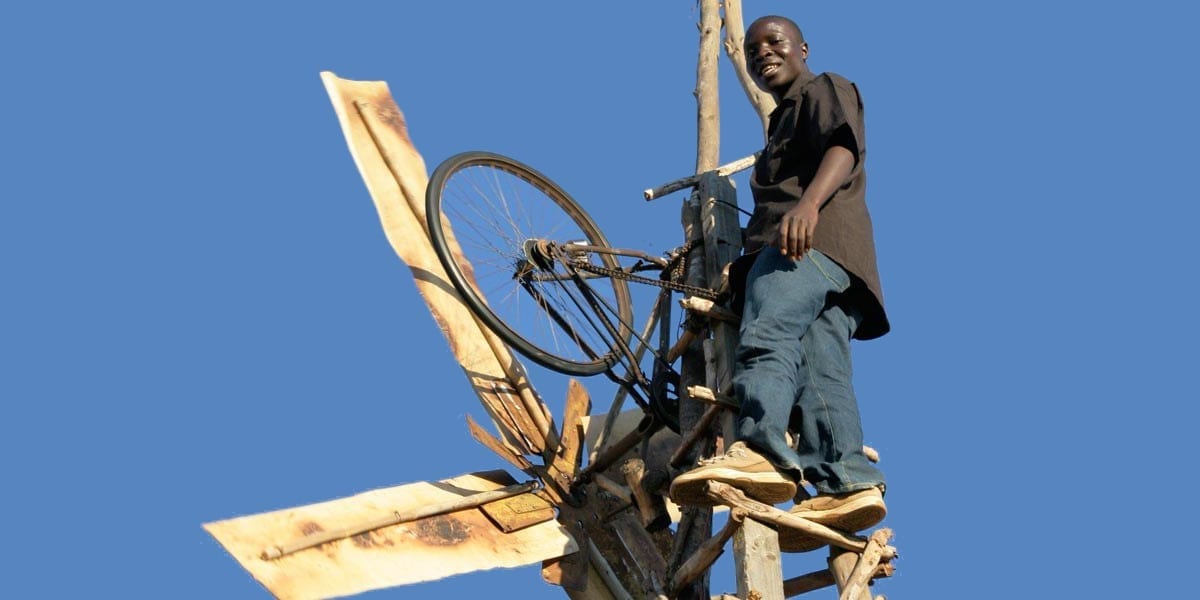 Kamkwamba up in his wind turbine power generator made from bicycle parts