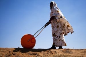 A woman in El Fasher, North Darfur, uses a Hippo Water Roller, a device for easily and efficiently carrying water. The "hippo roller", with its large drum capacity (usually 75 litres), frees women and children from having to spend a large portion of every day dedicated to collecting water for their households. The African Union-United Nations Hybrid Operation in Darfur (UNAMID) has distributed some 30,000 such rollers across Darfur. Photo by United Nations Photo / Flickr