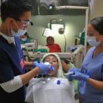 Dentists work on patients at a makeshift clinic in a hospital in El Salvador.