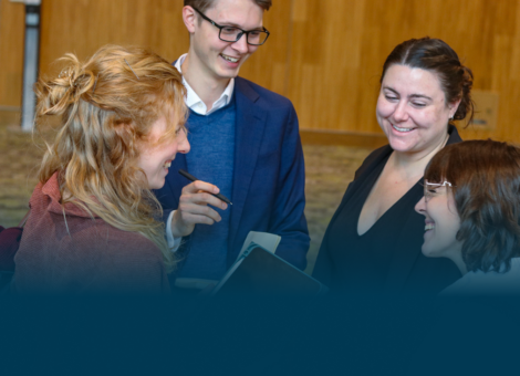 Four young adults stand in a circle smiling
